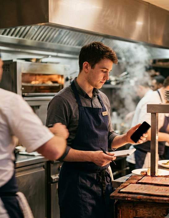 A waiter checking the book on a phone at the pass